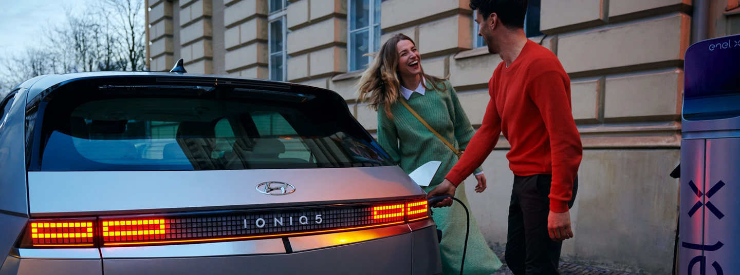 Man and woman laughing together and he charges IONIQ 5 car
