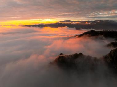 Mountain peaks above a sea of clouds lit by golden sunrise light