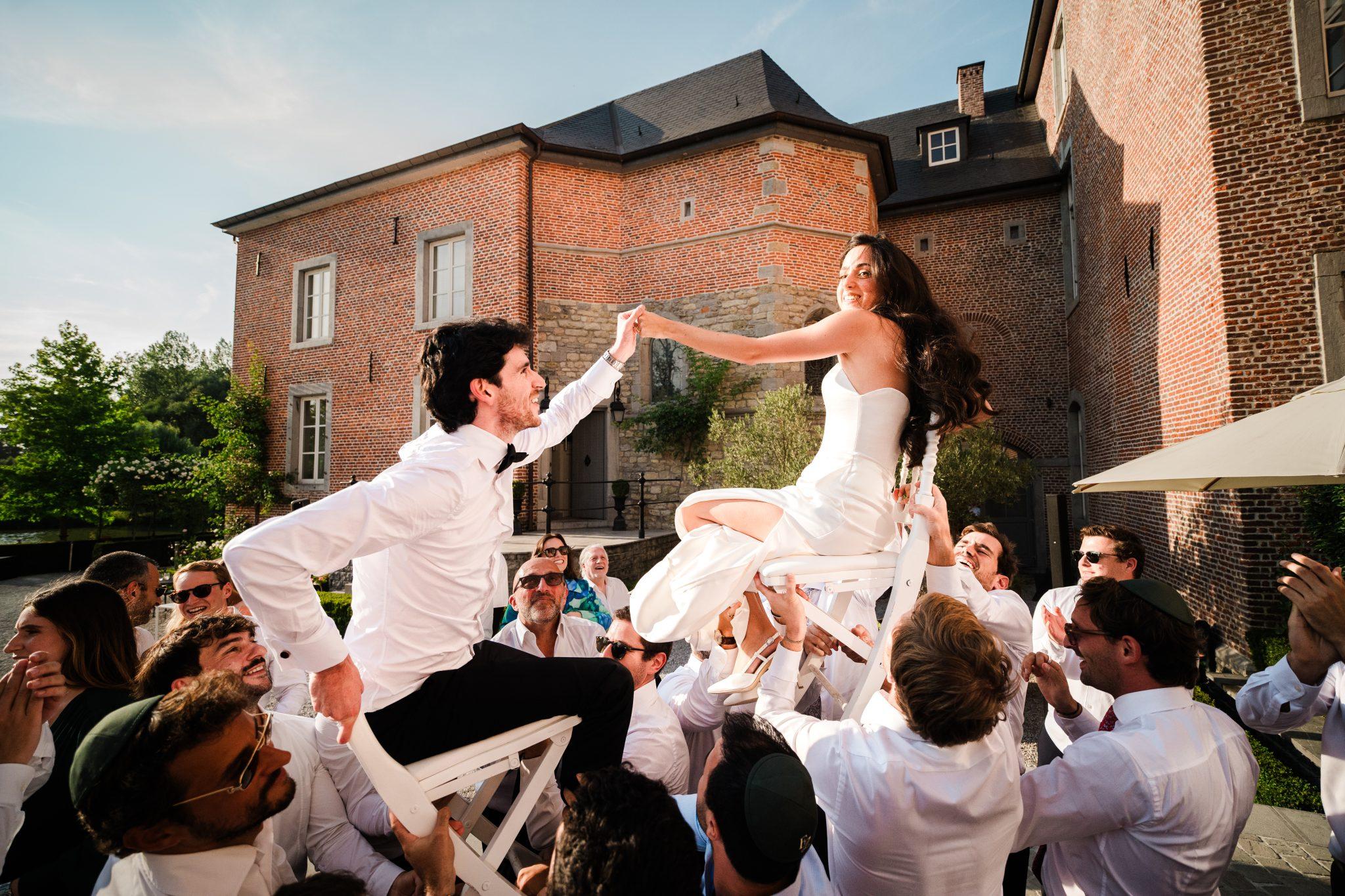 Eden and Zac wedding sitting on chairs lifted by guests
