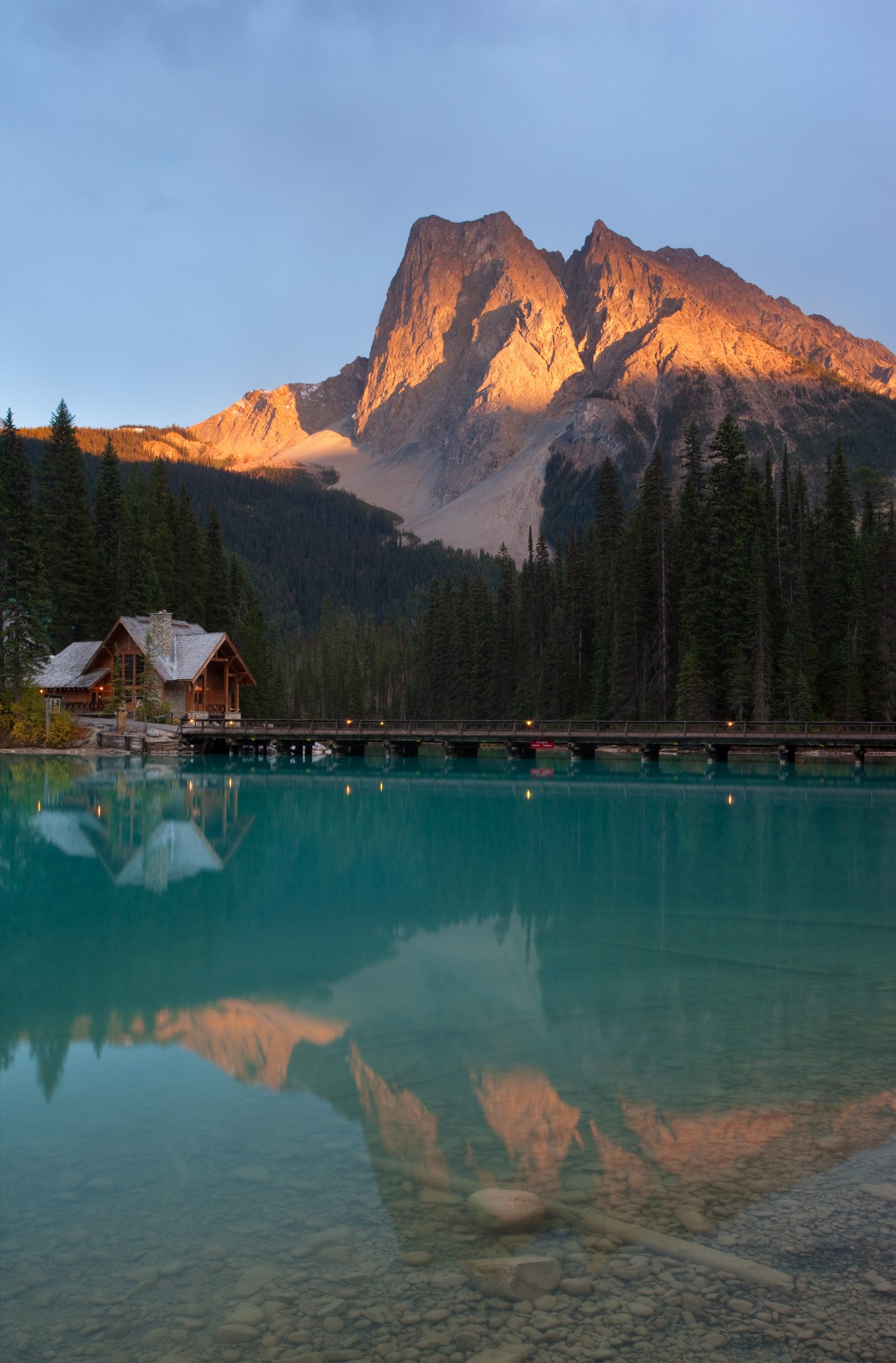 Emerald Lake Lodge and the footbridge, with last light on Walcott Peak and Mount Burgess reflected in the lake.