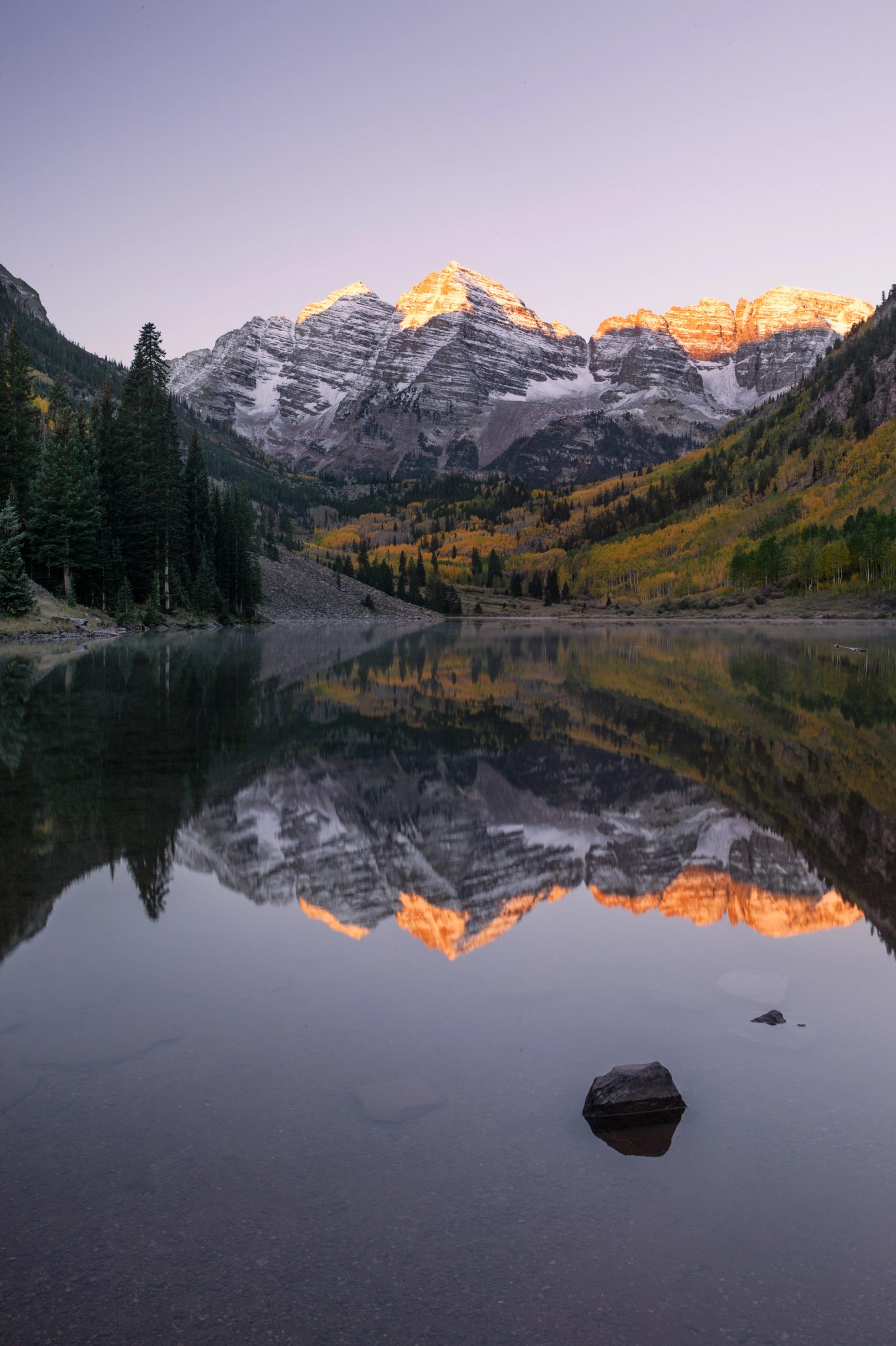 The Maroon Bells reflected in a still lake at dawn, Colorado.