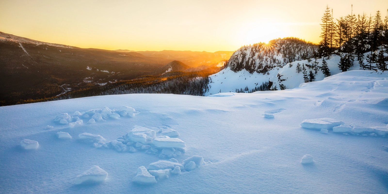 Sunrise over ridges from the summit of Tom Dick and Harry Mountain, Oregon, with wind-broken ice chunks scattered across the snow.