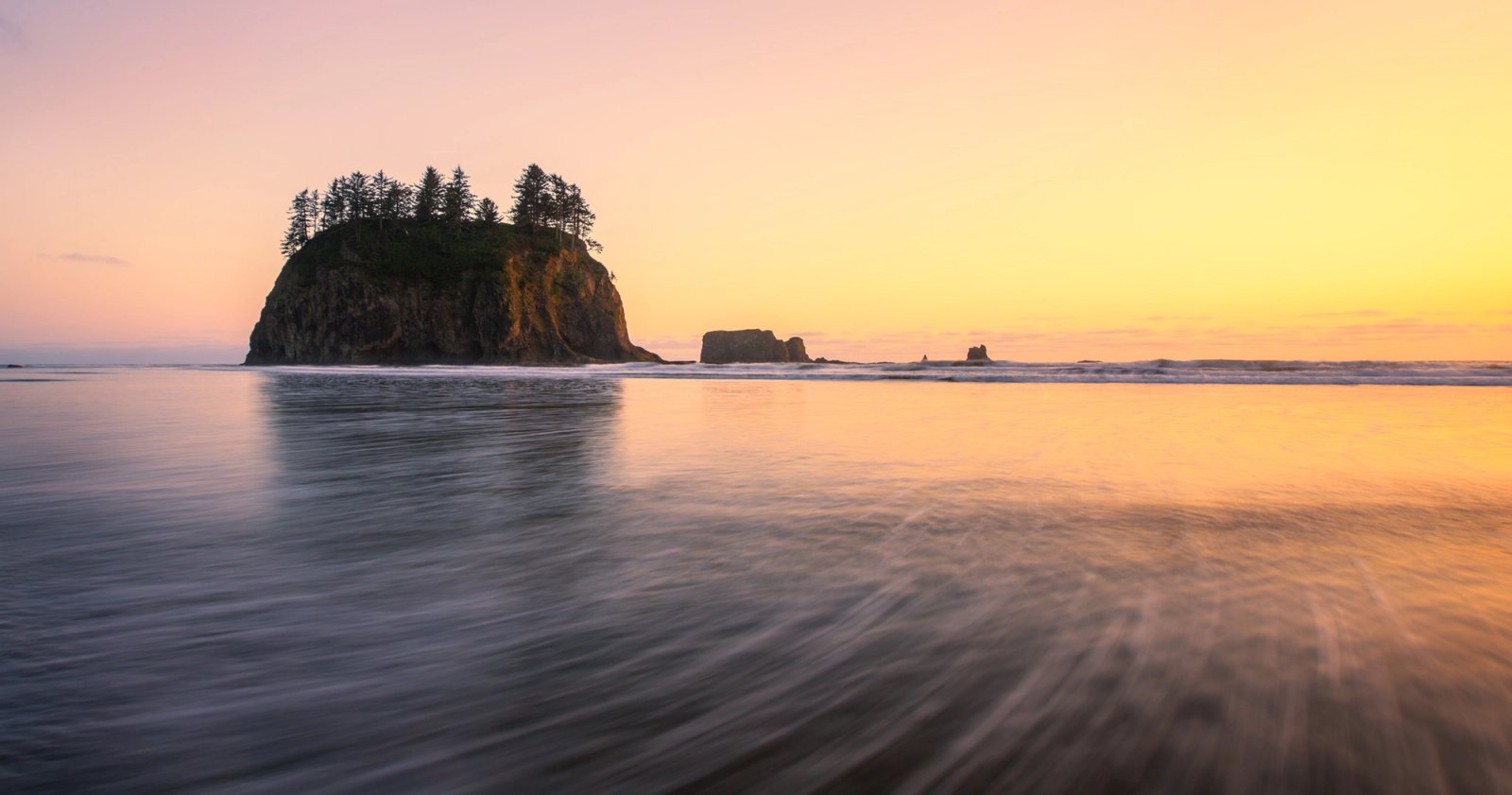Tree-topped sea stack at Second Beach on the Olympic Coast at sunset, wet sand and long-exposure water under a glowing horizon.