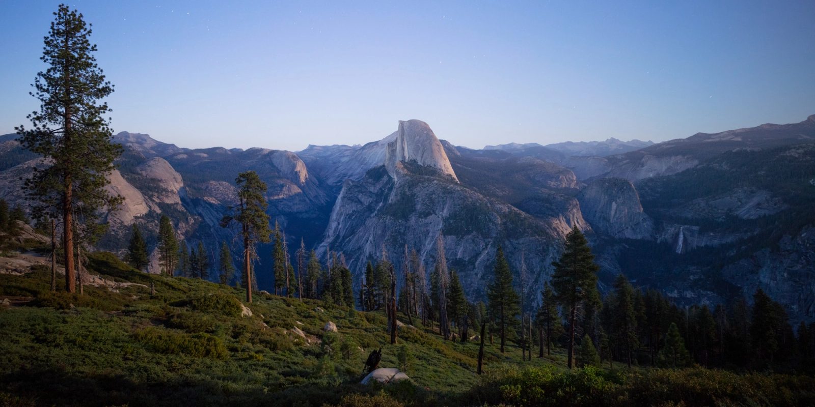 Half Dome at blue hour from Glacier Point, Yosemite National Park, California, lit by moonlight with stars coming out.