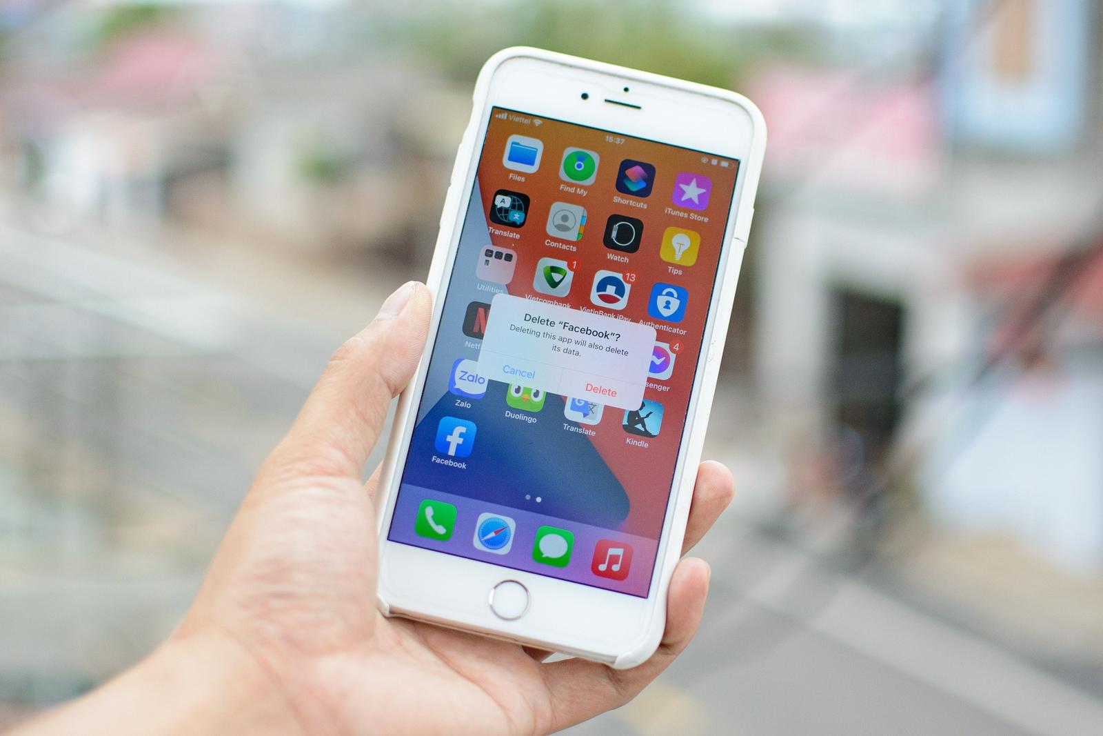An image of a person holding a smartphone while the screen shows the action to permanently delete their Facebook account.