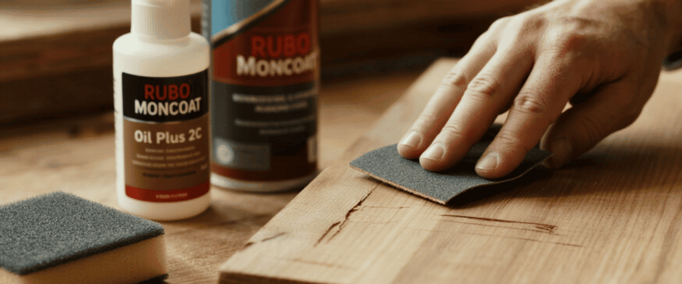 anding of a deeper scratch with 180-grit sandpaper on wood. Nearby bottle of Rubio Monocoat Oil Plus 2C and applicator pad