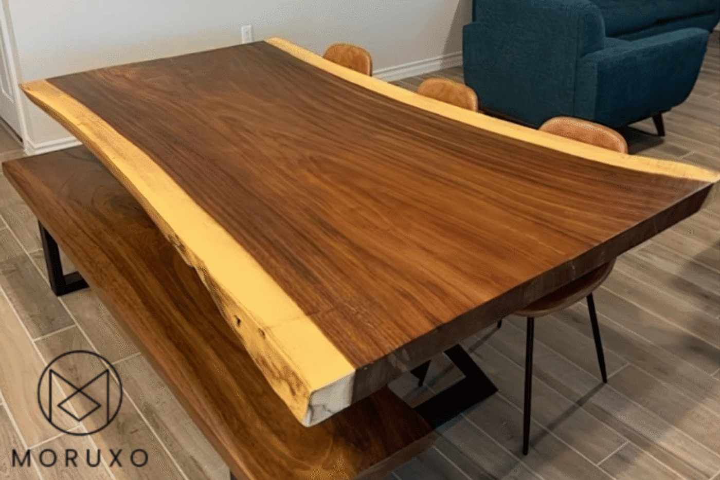 Live edge wooden dining table and bench with natural wood grain, smooth finish, and black metal legs in a modern room