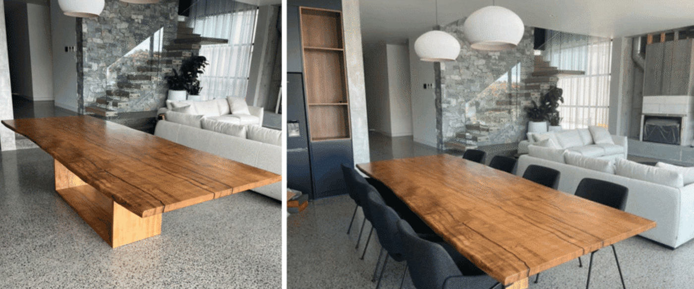Large live-edge wooden dining table with thick slab top and block base in modern open living room with sofa and stone staircase