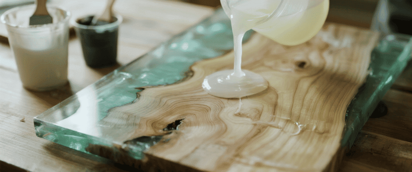 Pouring clear epoxy resin onto a live edge wood slab to create a smooth, glossy, and durable surface for furniture or decor.