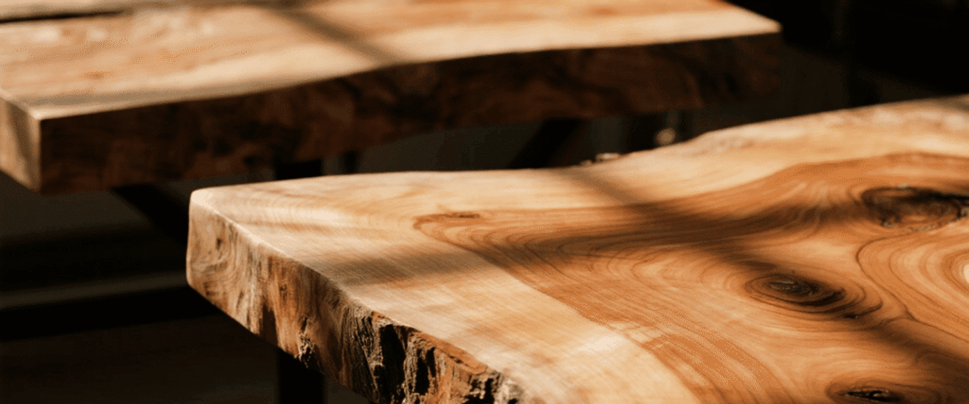 Sunlit live-edge wooden table surface showing natural grain, knots, and smooth polished edges with warm tones and soft shadows.