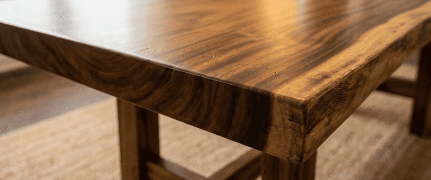 Smooth, polished wooden table corner with rich grain patterns, warm tones, and sturdy legs on a woven rug beneath