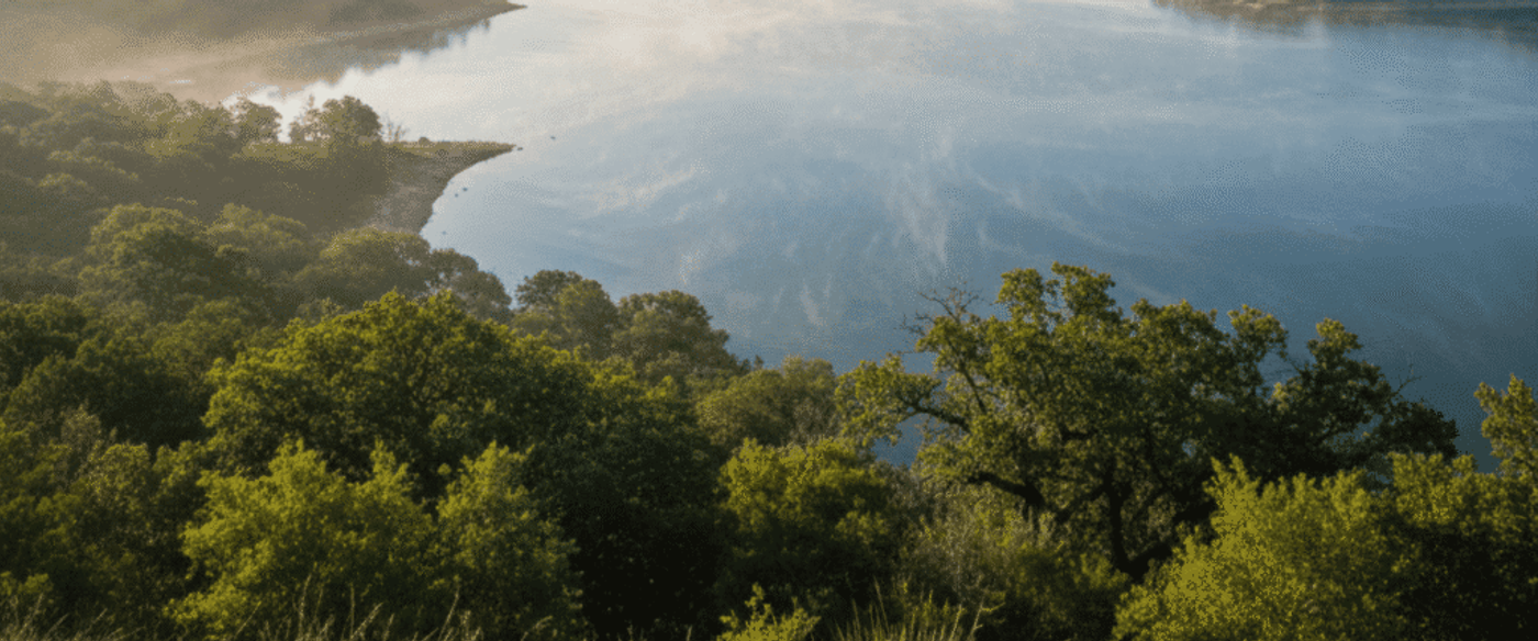 Lake Travis in Texas Hill Country, humid subtropical atmosphere, bright sunlight, mist rising over water