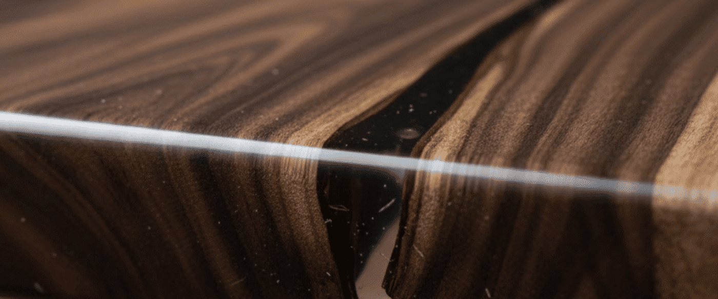 Polished live-edge walnut slab table with clear epoxy river filling a natural wood crack, smooth glossy finish and rich brown grain