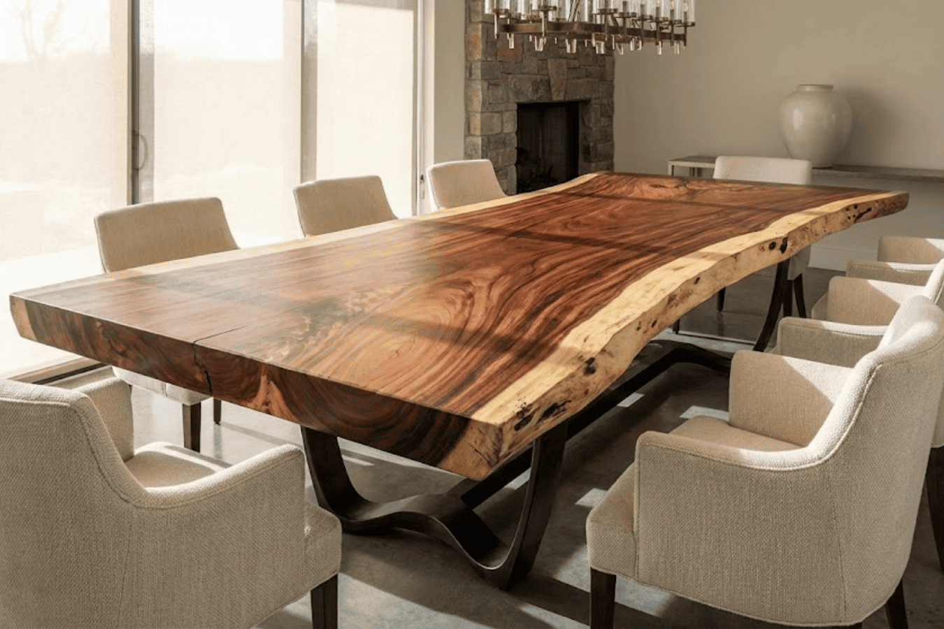 Solid live-edge walnut dining table with flowing grain set among eight upholstered beige chairs in sunlit modern dining room