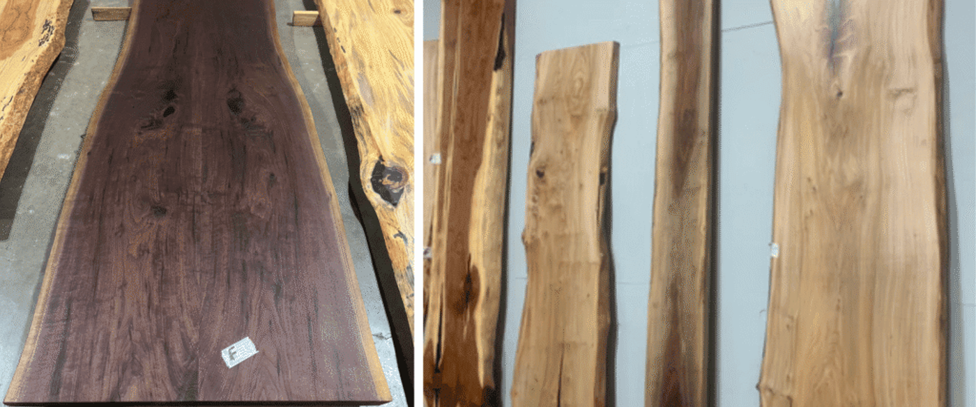 Vertical live-edge wood slabs of varying widths and grain patterns leaning against a pale wall in a workshop or showroom