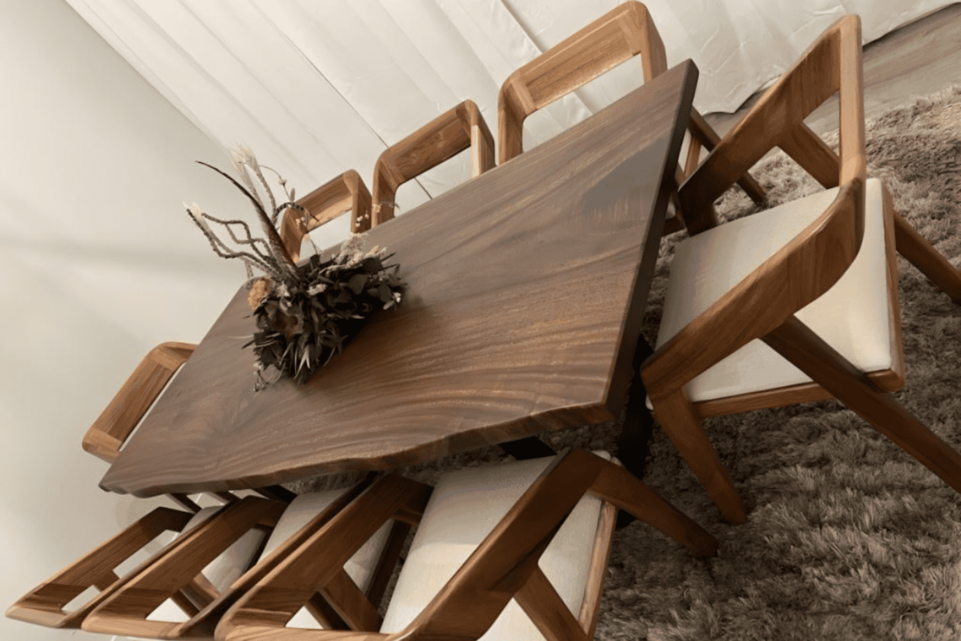 Modern wooden dining table with six matching chairs and a centerpiece arrangement