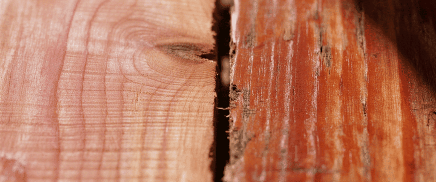 Rough red-stained wooden boards with visible grain, knots, and a narrow dark gap between two planks, close-up texture.
