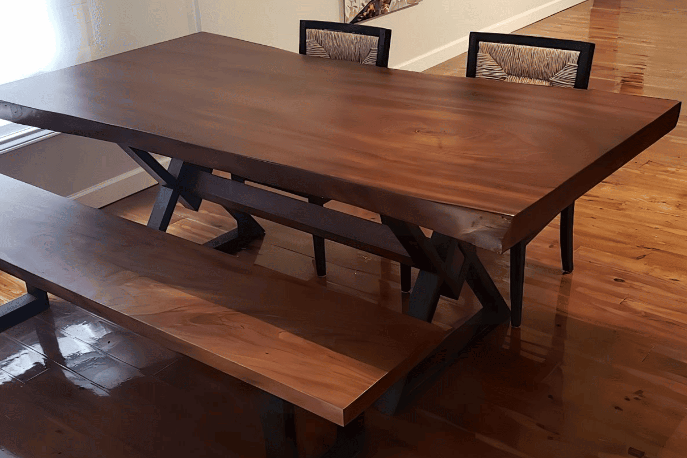 Solid walnut dining table with matching bench and chairs on polished hardwood floor in a bright, modern dining area.