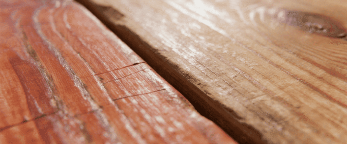 Rustic wooden planks with visible grain, knots, and a narrow gap between boards, warm reddish and tan tones, close-up texture.