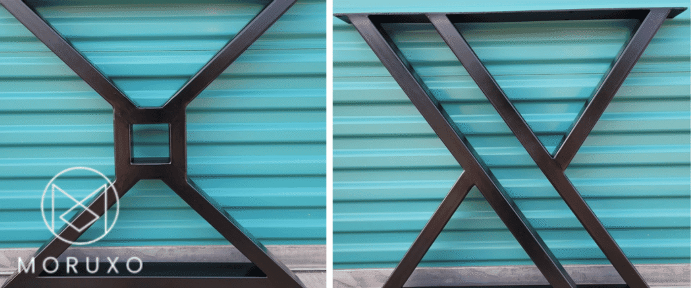 Black metal table base with geometric X-shaped supports and square center, photographed against a teal corrugated metal background.