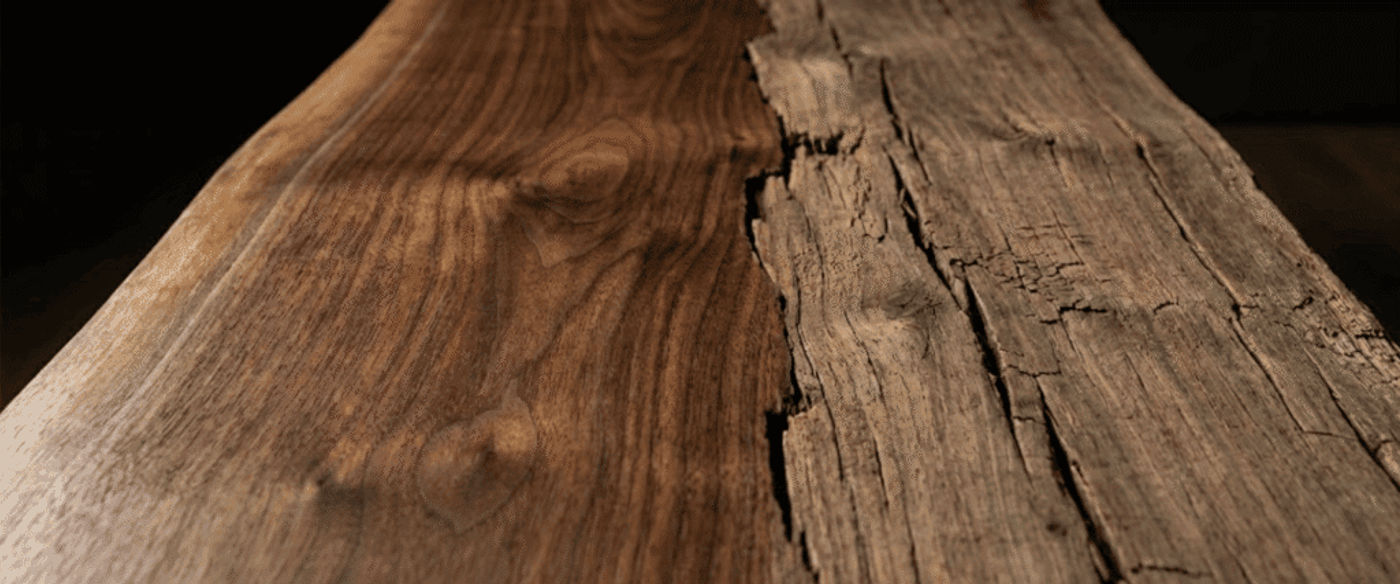 Polished walnut slab meeting rough, cracked reclaimed wood along a center seam, showing rich grain, knots, and weathered texture