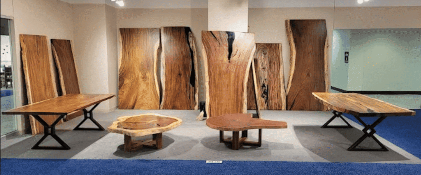 Live showroom of large natural wood slab tables and countertops with rich grain patterns and modern metal bases, gallery display.