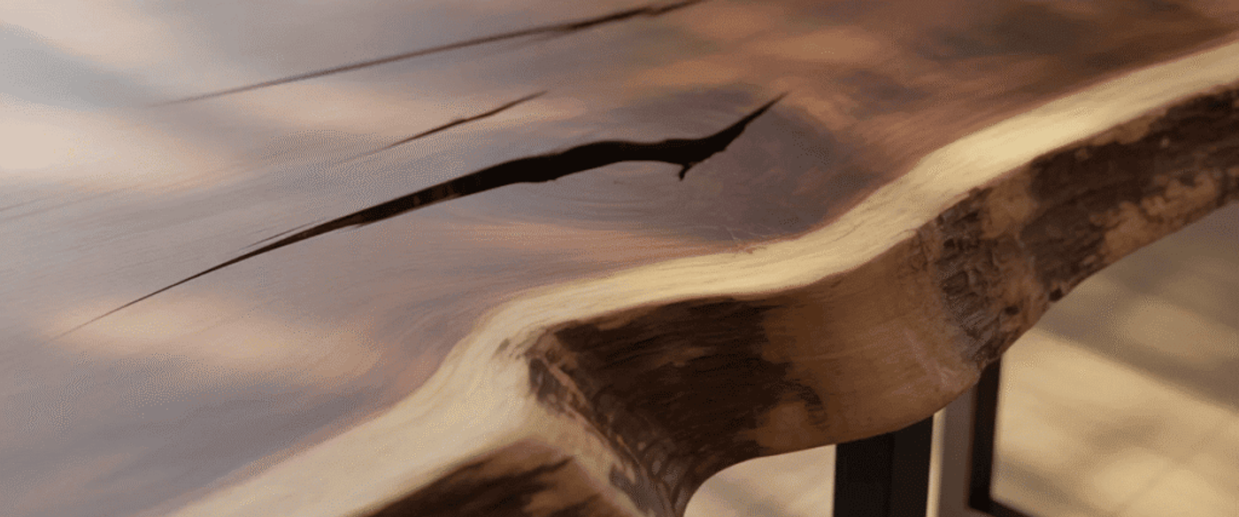 Live-edge wooden table with rich grain, a natural crack filled darkly, smooth polished surface and sturdy metal legs, warm tones