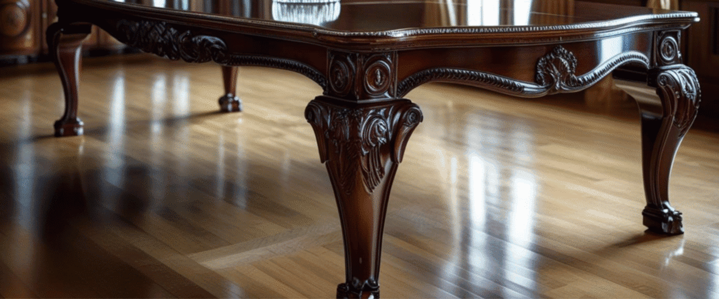 Ornate wooden table leg with detailed carvings on polished hardwood floor.