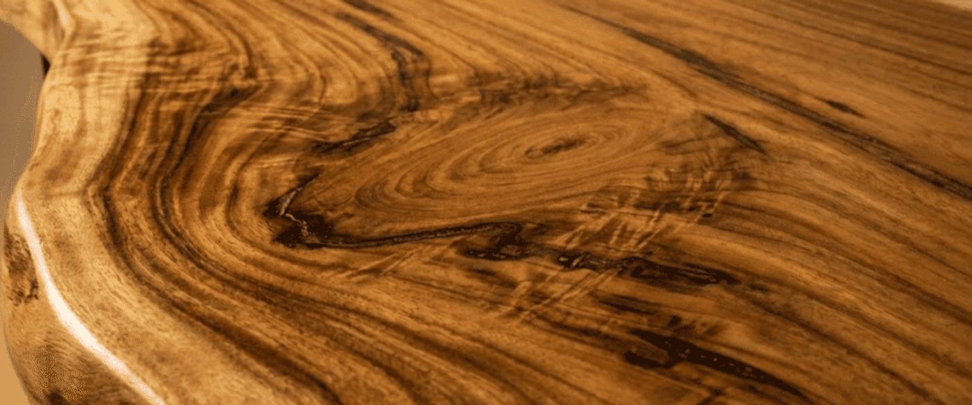 Hand-sanded live-edge walnut tabletop with swirling grain patterns, knots, and a smooth satin finish highlighting warm honey-brown tones