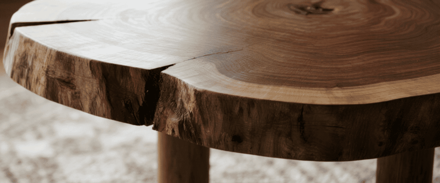 Natural wood table with live edge design, showcasing rich grain patterns and organic cracks for a rustic, handcrafted look.