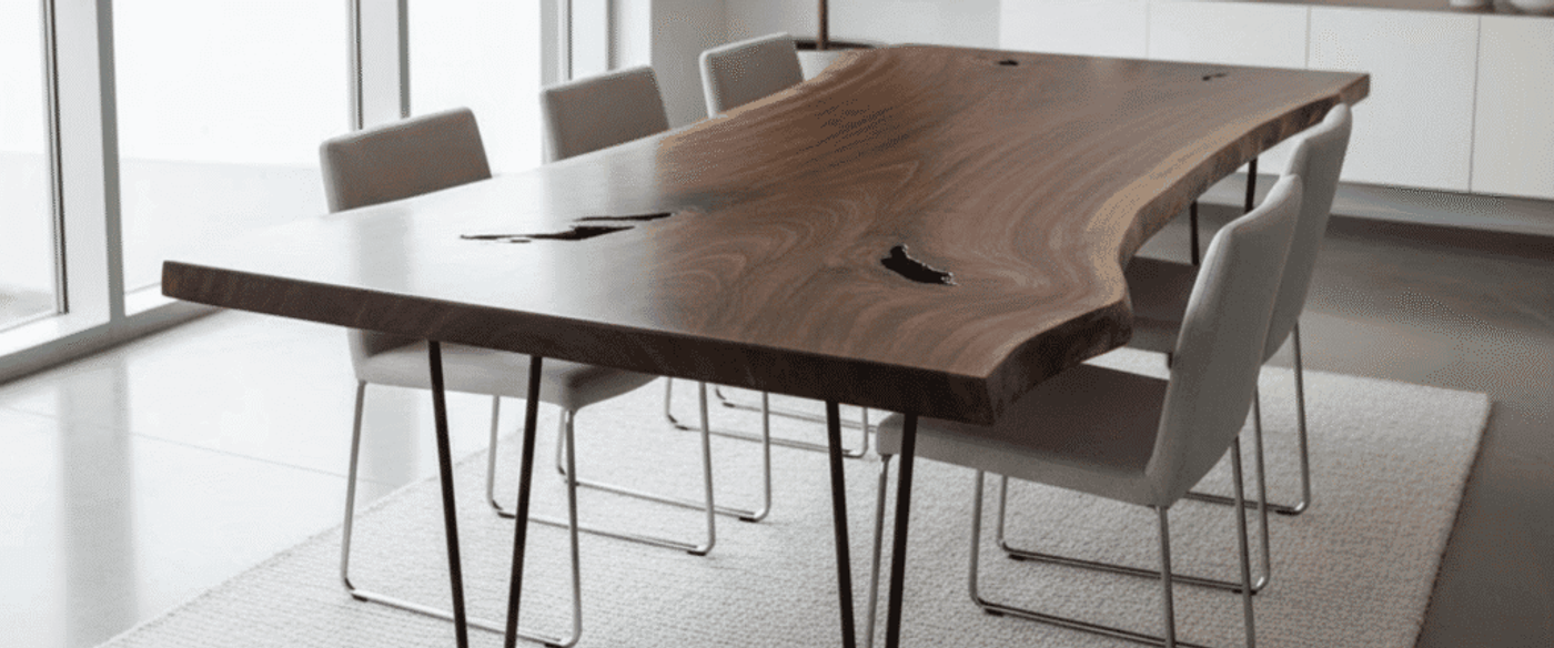 Live-edge walnut dining table with hairpin legs, six gray upholstered chairs, large windows, pendant light, and potted fiddle leaf fig
