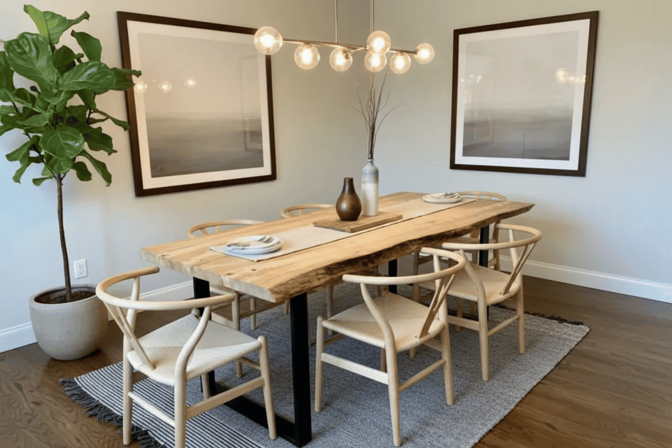 Live-edge wooden dining table with black metal legs surrounded by four light-wood wishbone chairs on a gray rug.