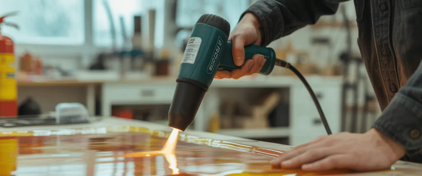 Heat gun in use to shape or soften material on a work surface.