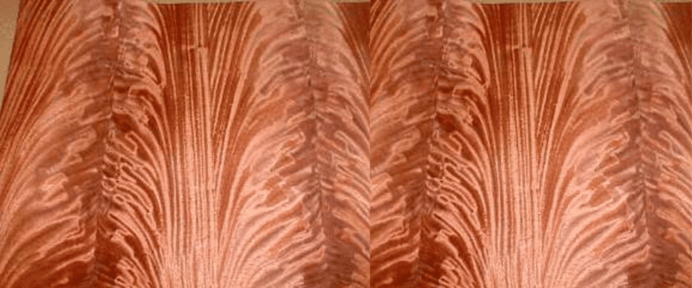 Warm, rippled wood grain pattern with symmetrical, feather-like figures and rich reddish-brown tones.