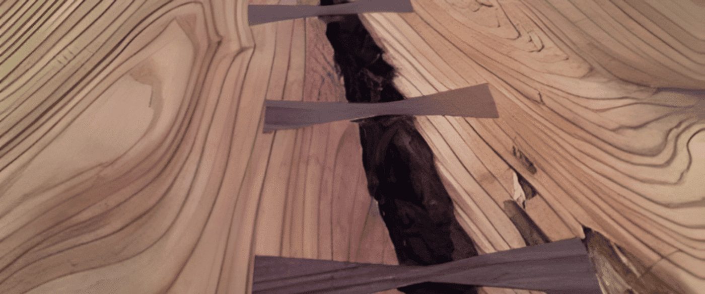 Live-edge wooden table with visible grain and butterfly joints bridging a long natural crack down the center.
