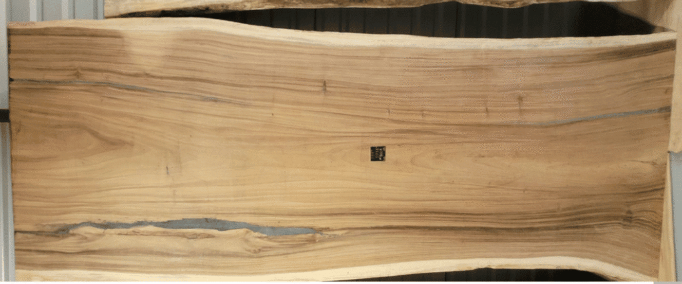 Wood slab with natural grain patterns and uneven edges, showing raw timber surface.