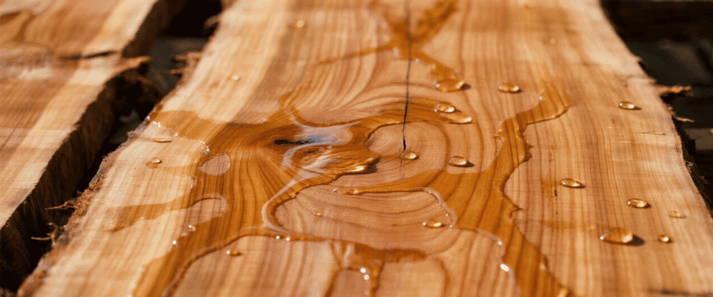 Close-up of a live edge wooden slab with water droplets highlighting the grain pattern and natural texture of the wood