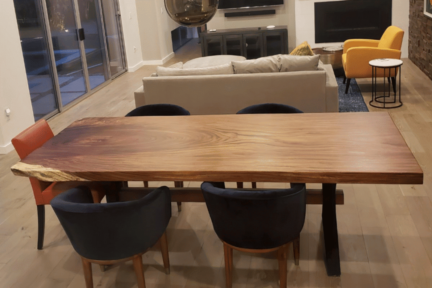 Live edge wood dining table with mixed color chairs in modern open living room.