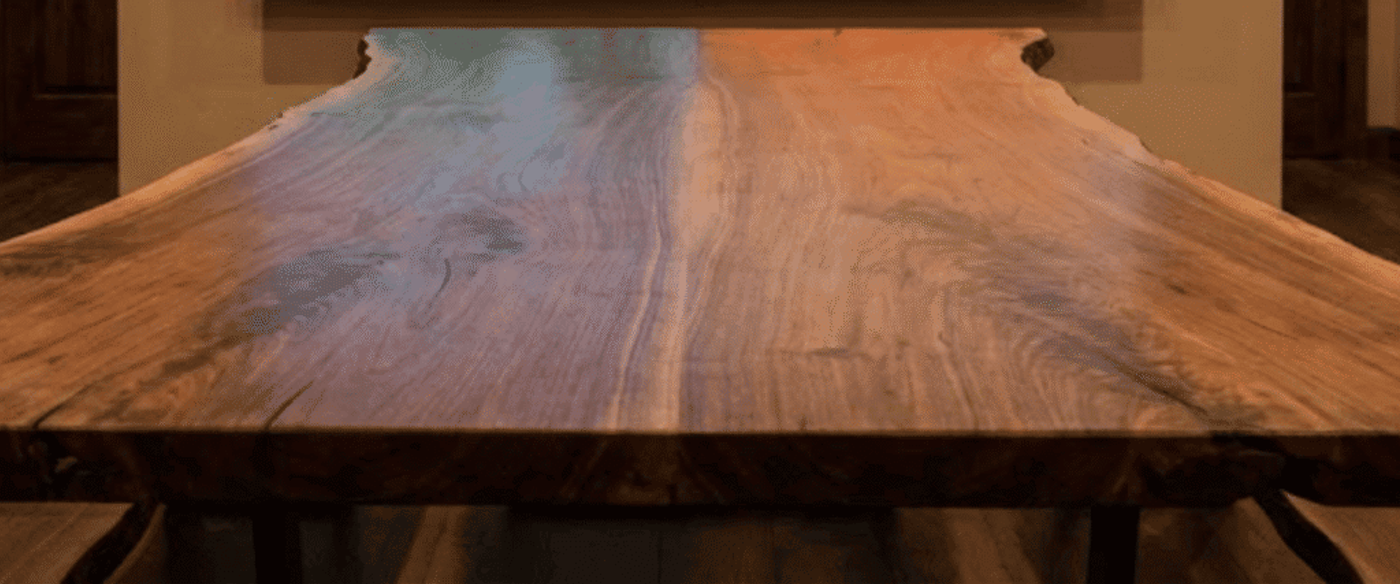 Live-edge wood conference table in a warm room with a wall display comparing East Texas (humid, rainy) and West Texas (dry, cracked, high heat) climate