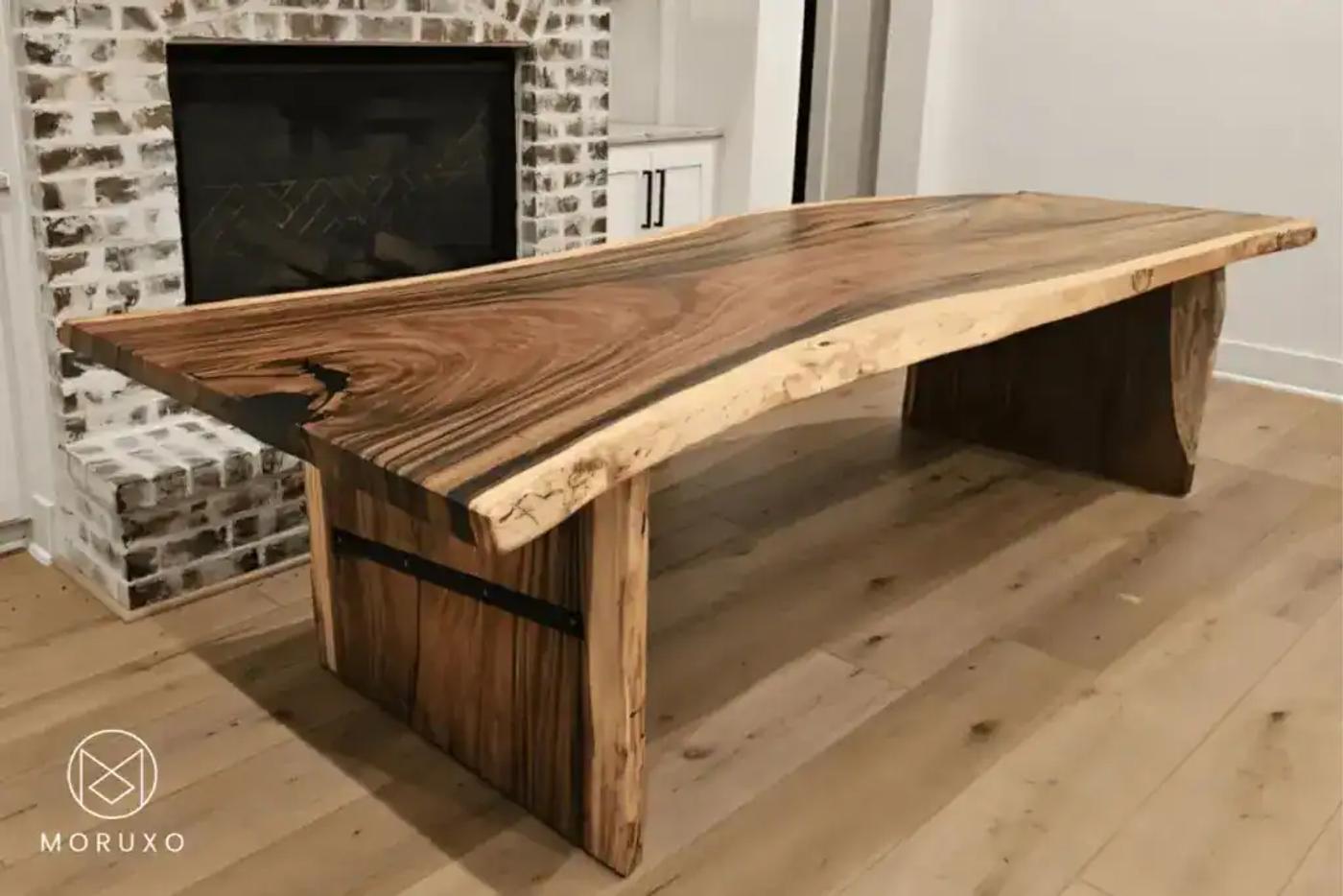 Live-Edge-Table-of-Moruxo-With-Wood-Legs-In-Front-of-a-Fireplace