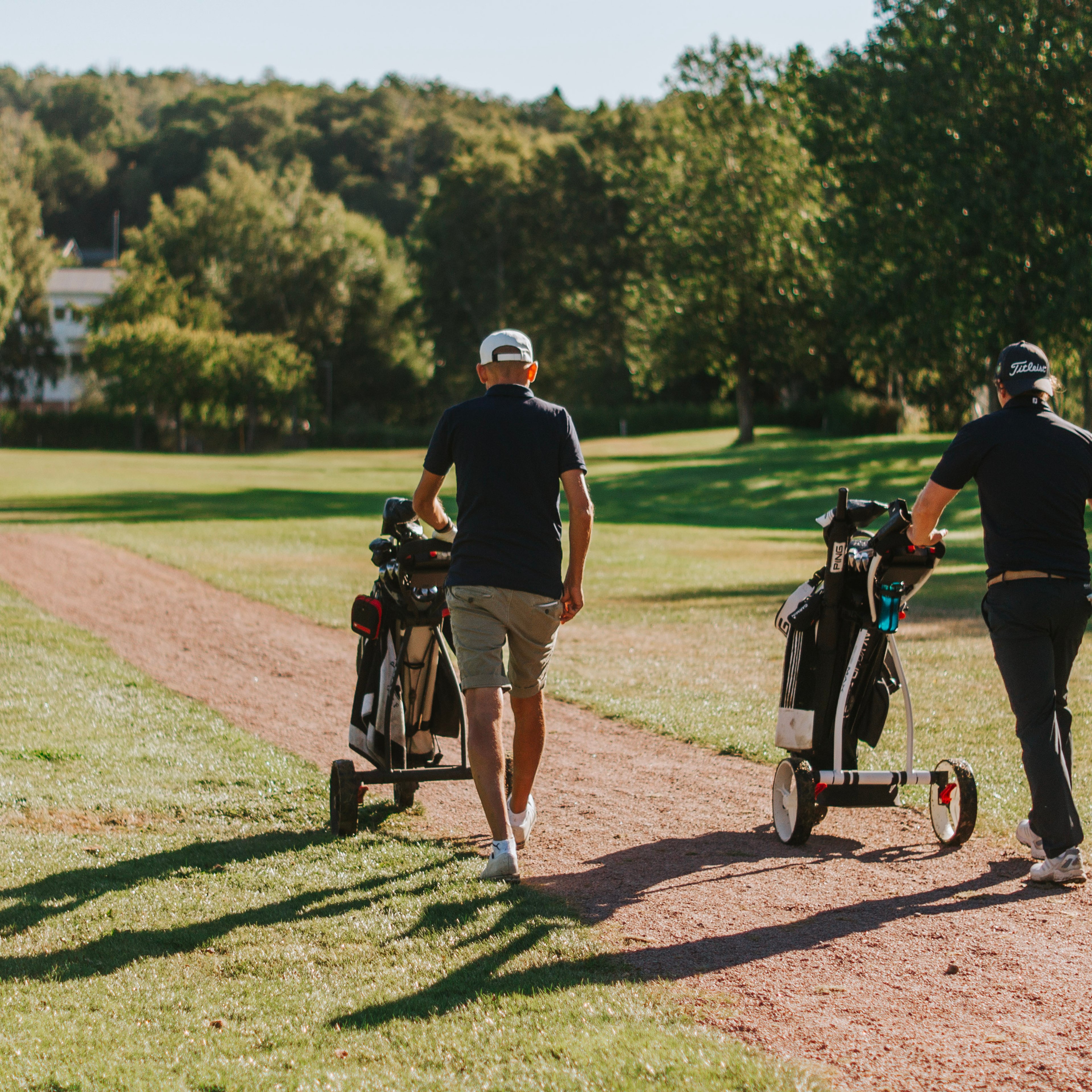 Tre personer med golfvagnar på en golfbana