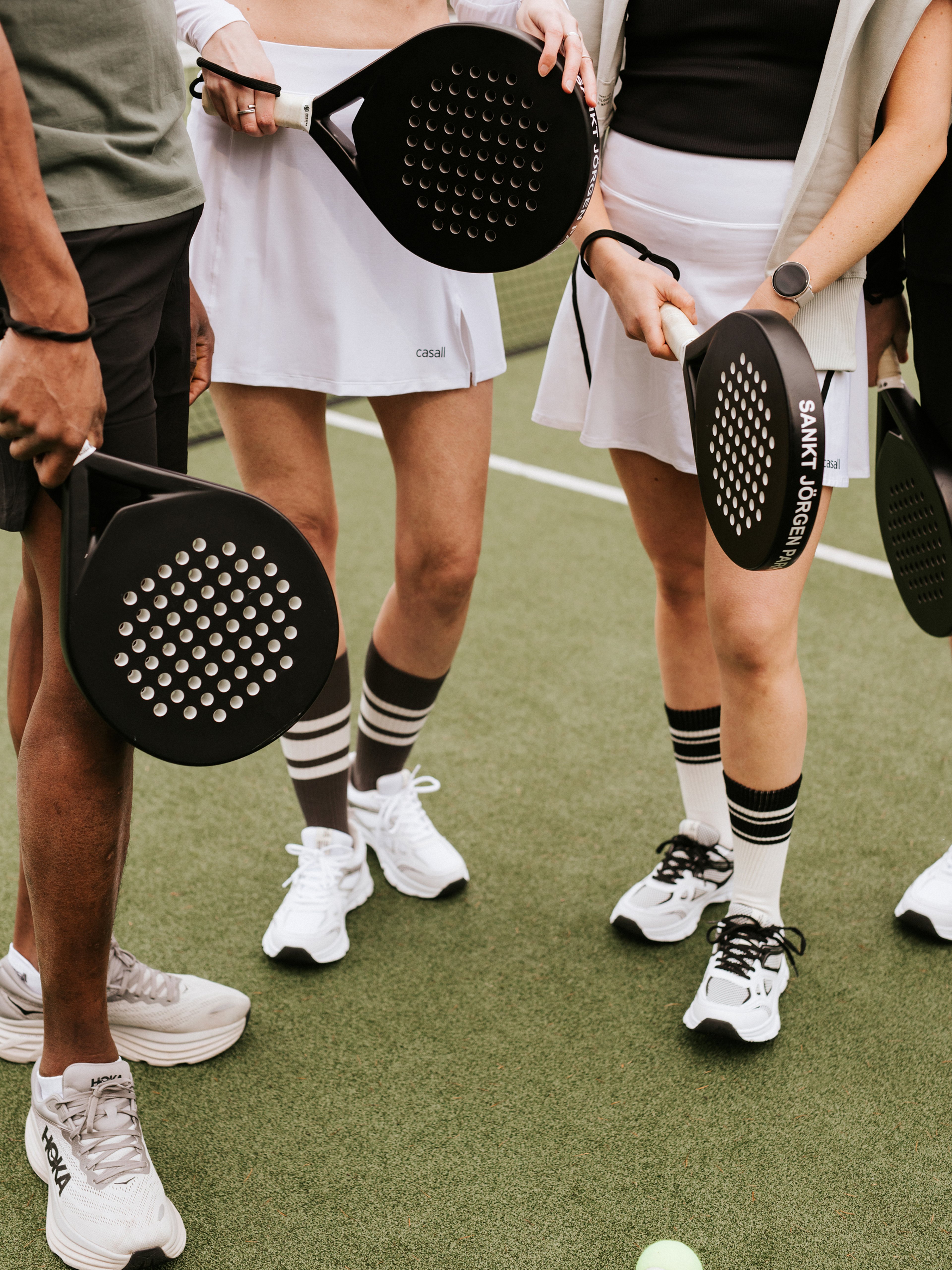 En grupp som står i en ring med varsitt padelrack
