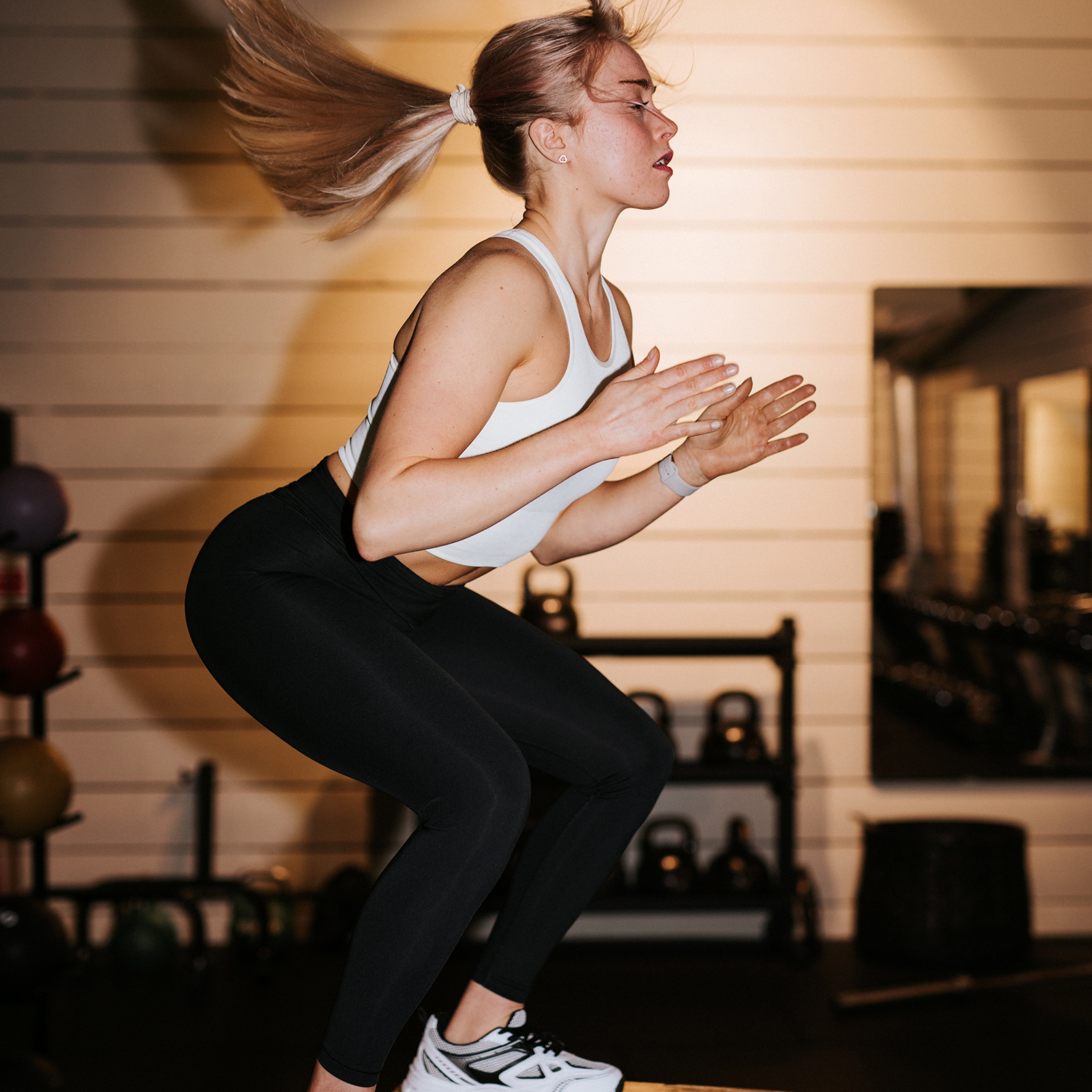 Kvinna hoppar upp på en box på gym