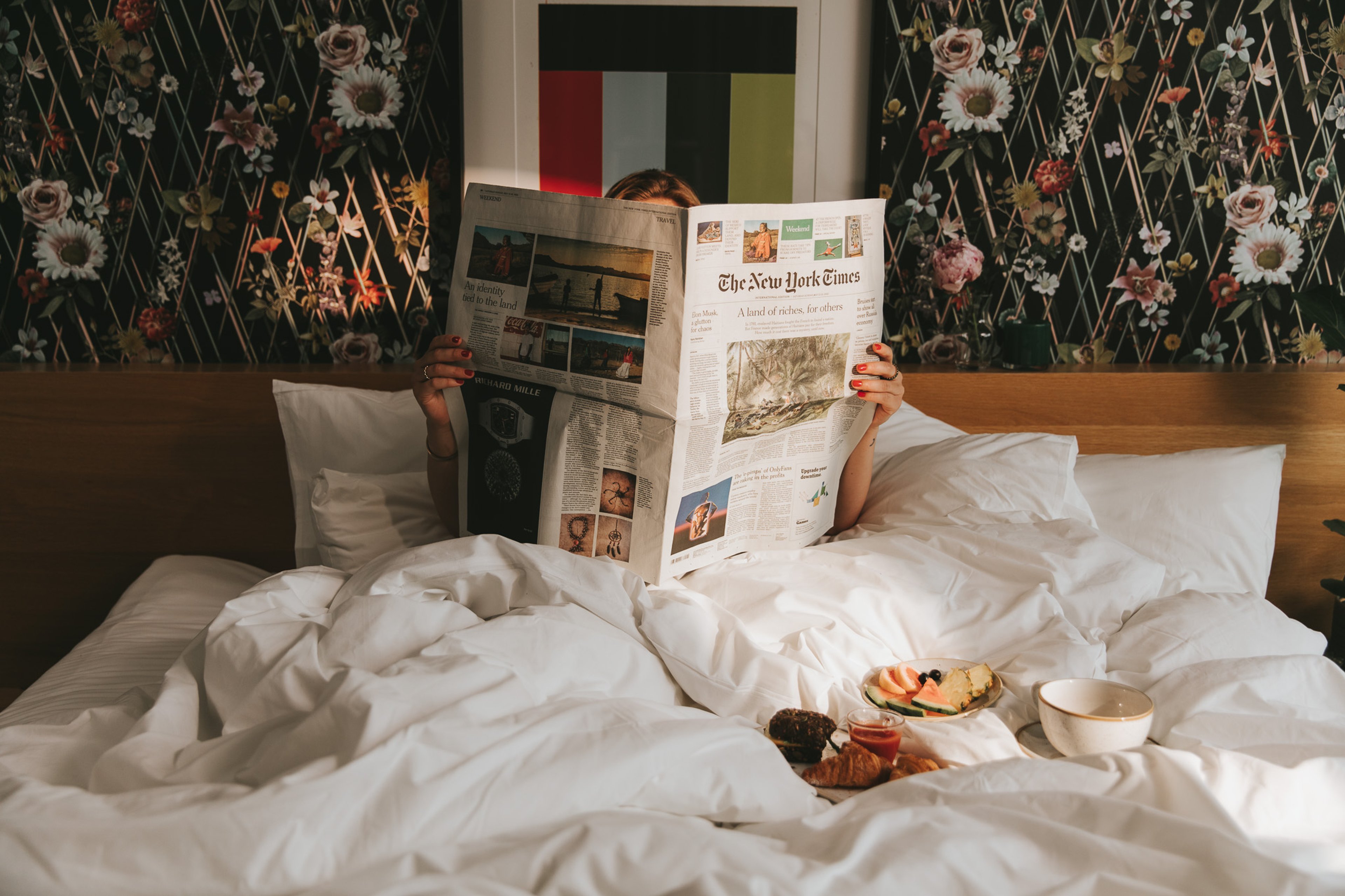 Tjej som läser tidningen i sängen