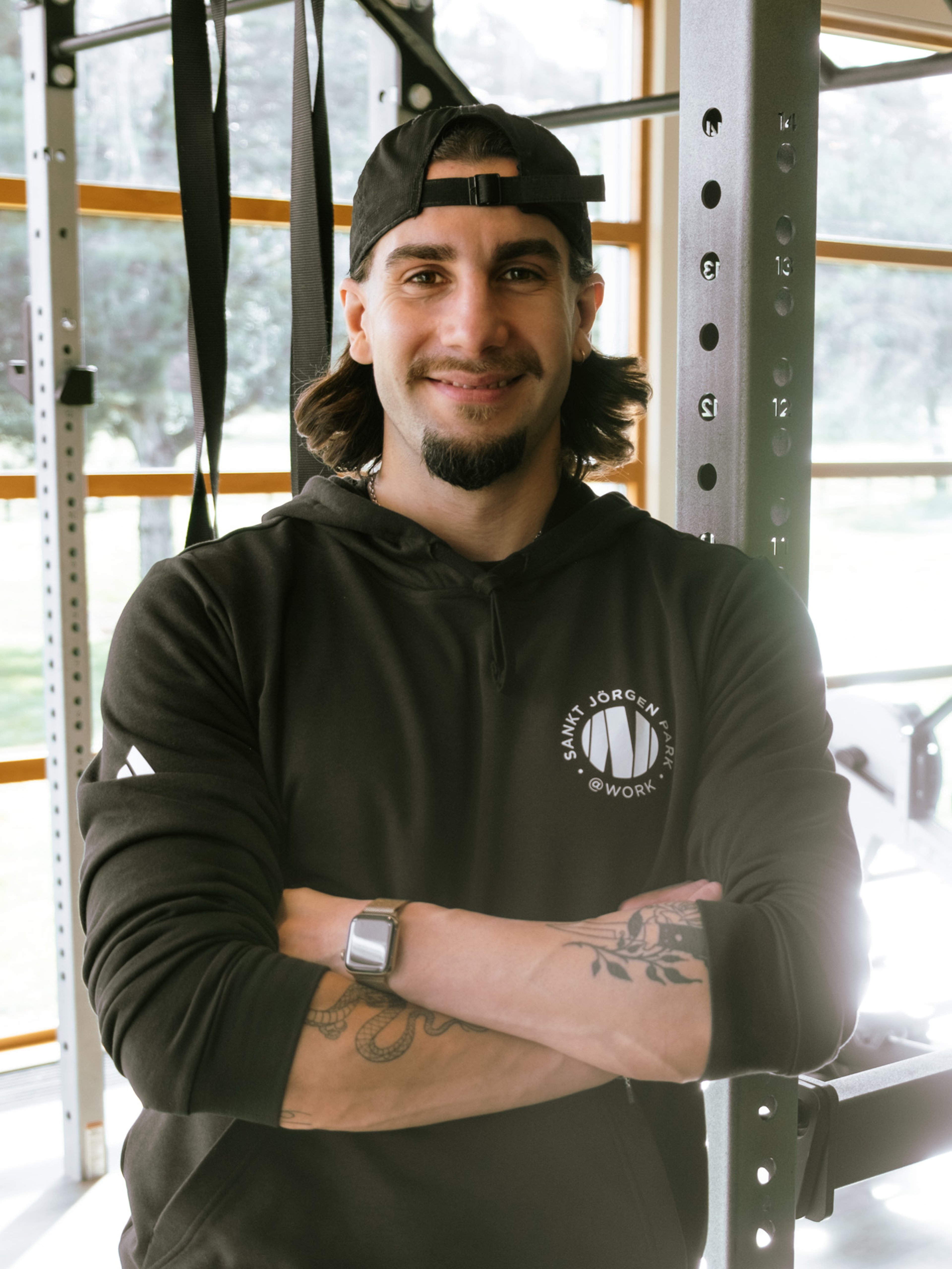 Man med tatueringar och skägg som sitter ner