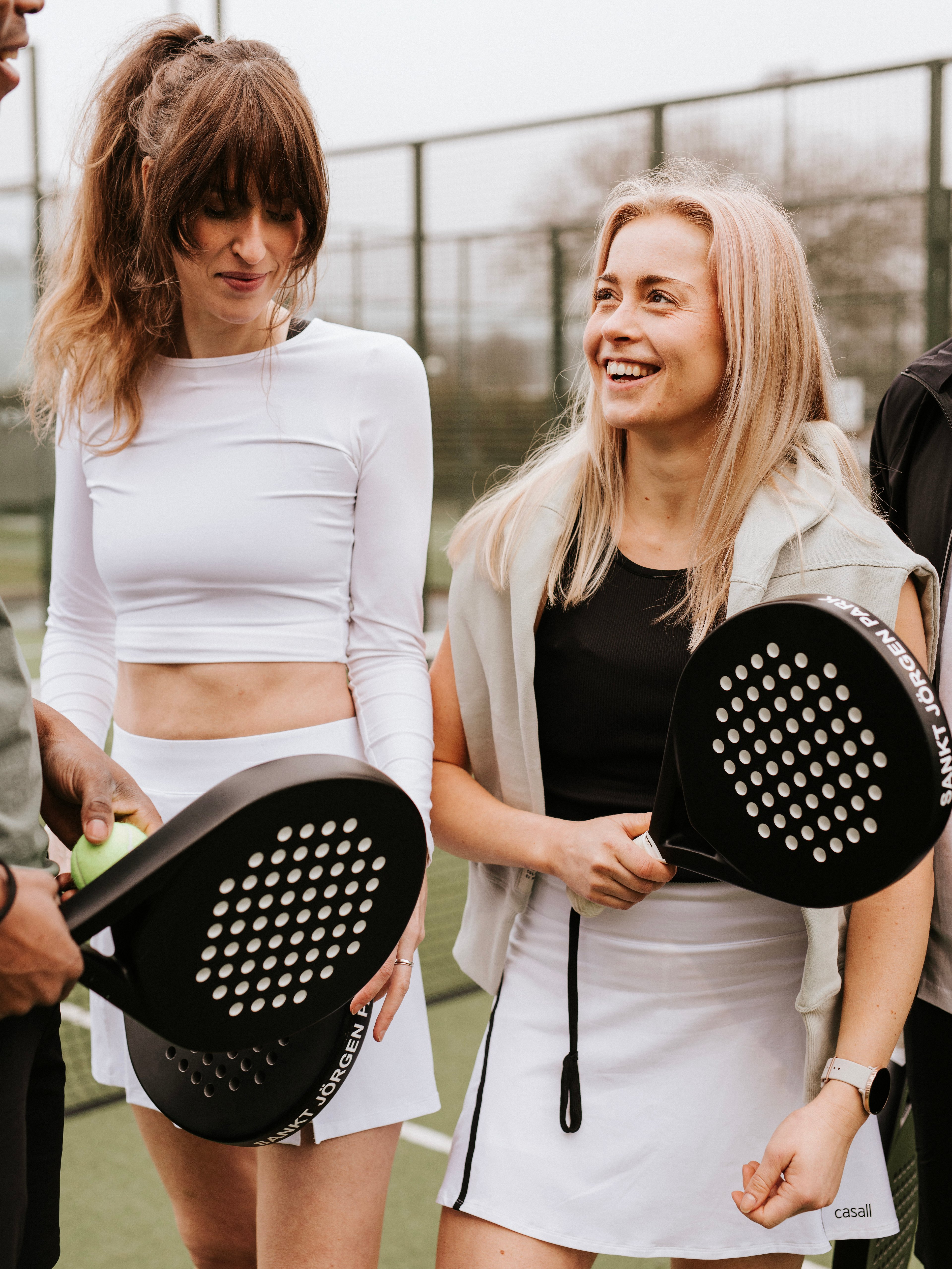 En grupp glada människor utomhus med padelrack i händerna