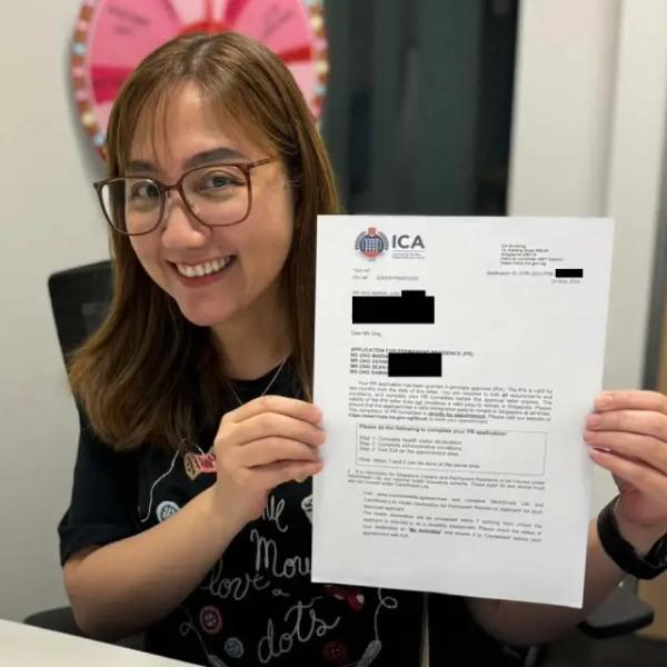 Maria, a Singapore Top Immigration client, holding their ICA approval letter