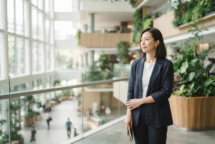 Singapore PR healthcare: a woman in a bright modern public hospital atrium with greenery