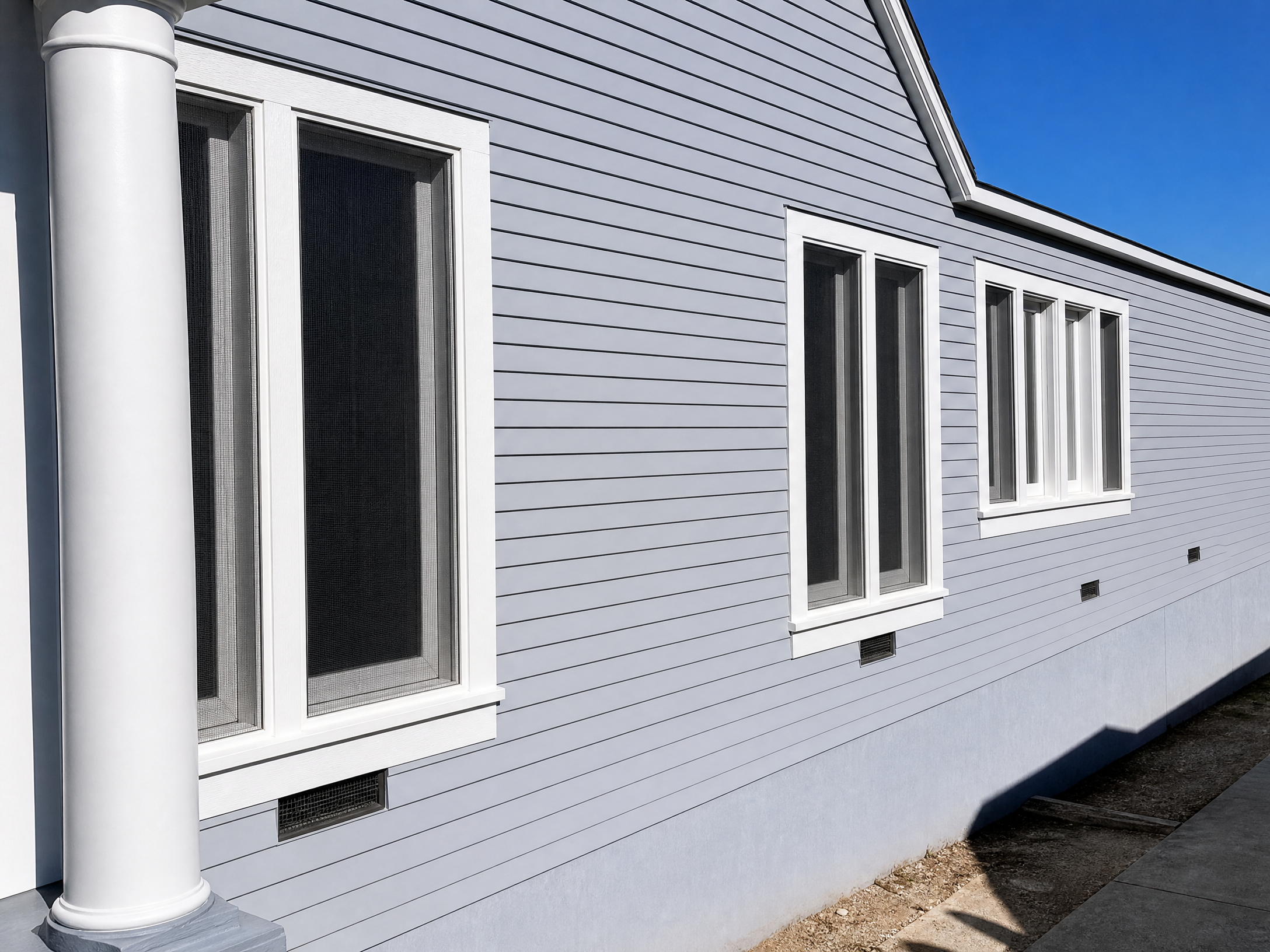 Light gray house siding with white-framed window screens installed by Screen Masters