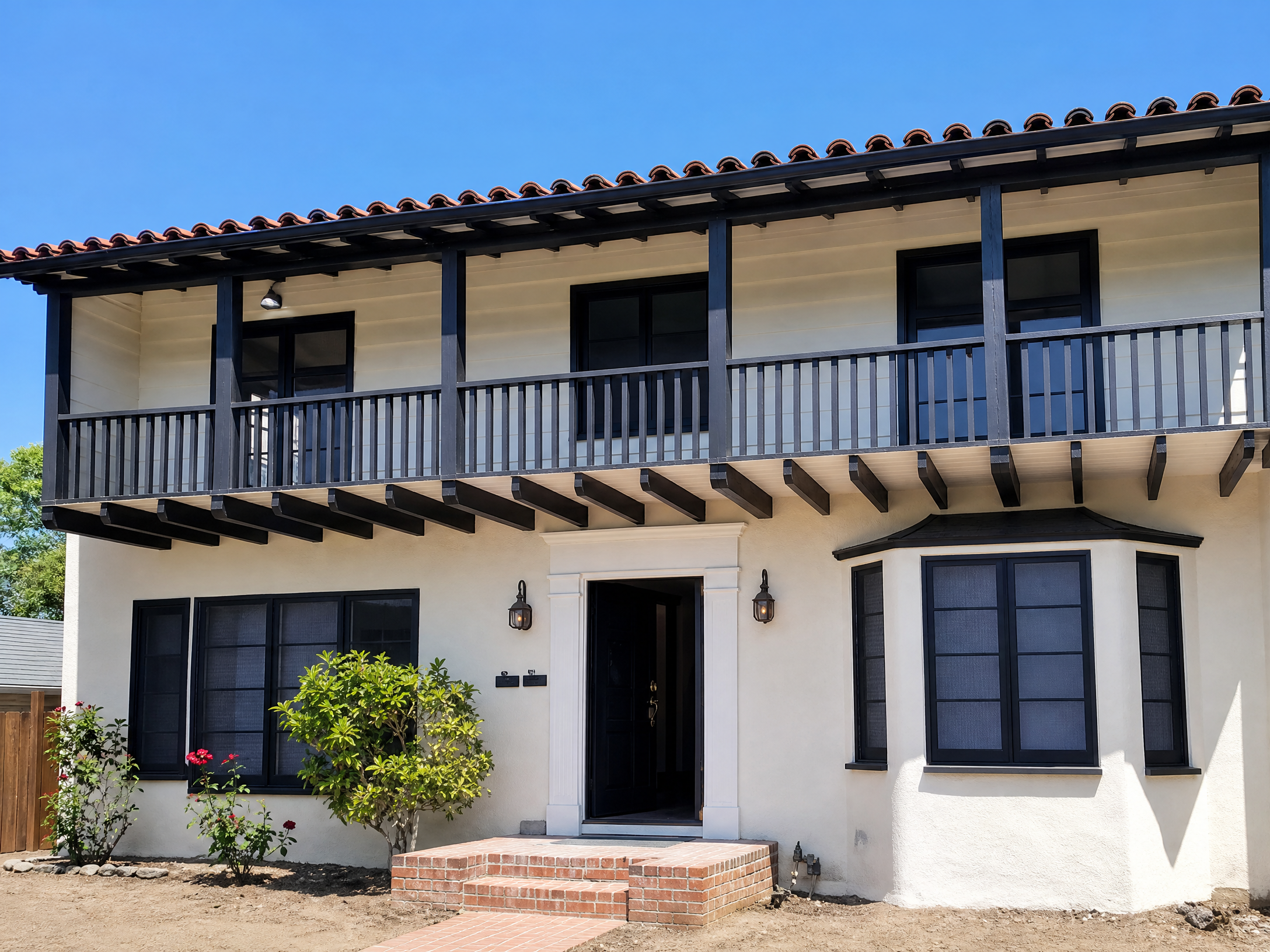 Two-story cream stucco house with dark trim and window screens installed